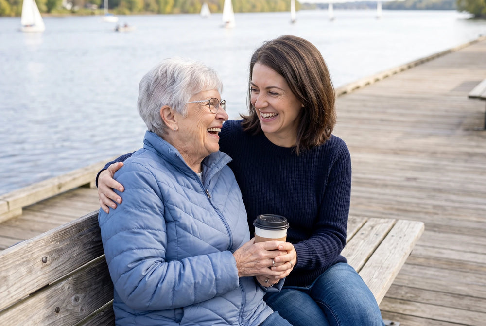 Laura Hopson laughing with her mother on a bench by the river